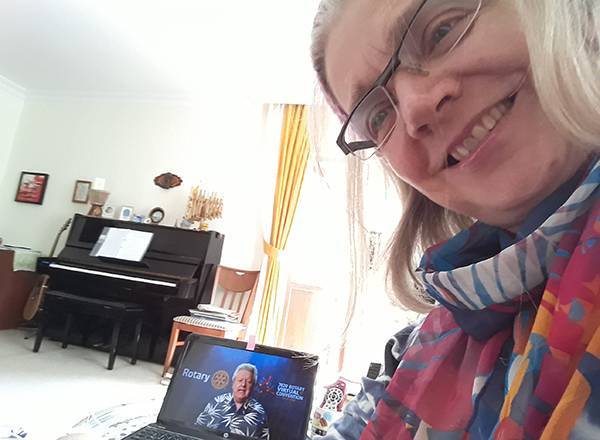 Erin Maloney assistindo à gravação da Convenção de 2020 (na tela, seu irmão Mark Maloney, presidente do Rotary International em 2019-20.